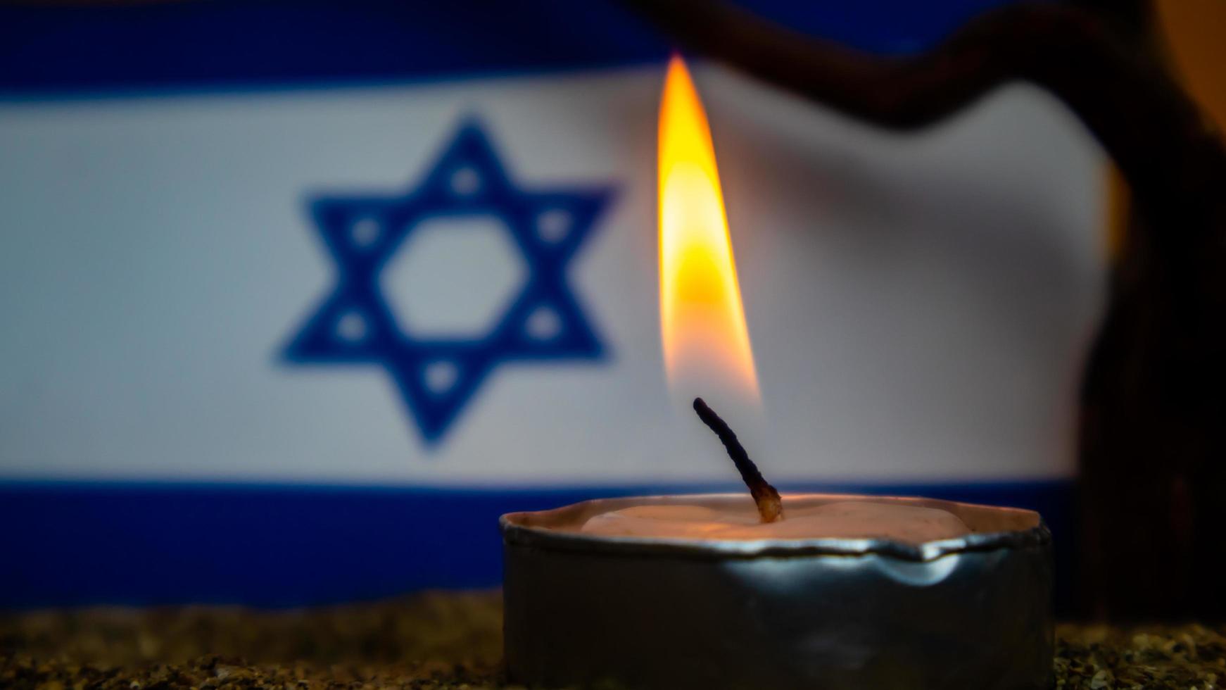 Israeli flag and candles burning in front of it, Holocaust memory day photo