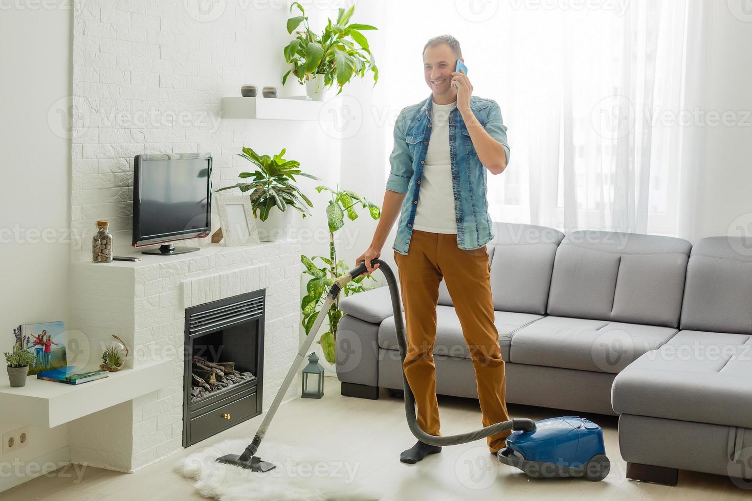 Coronavirus pandemic. A man with a vacuum cleaner in his apartment. Home Office. Quarantine. Remote work. A man in a business shirt and underpants holds. photo