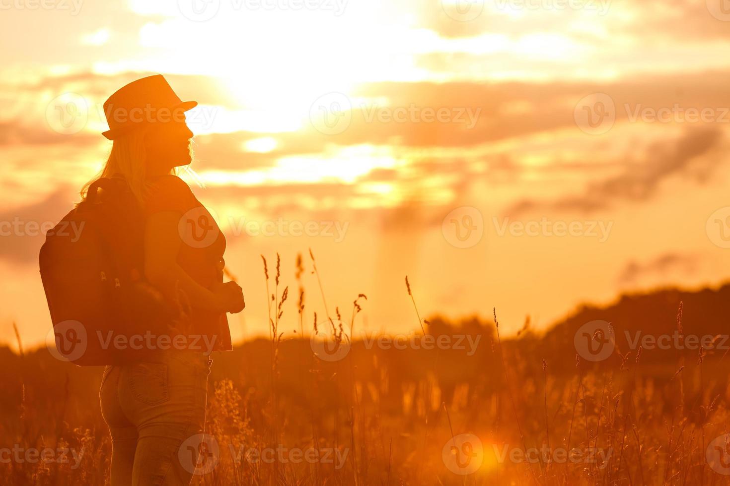 silueta de mujer esperando el sol de verano en la pradera foto