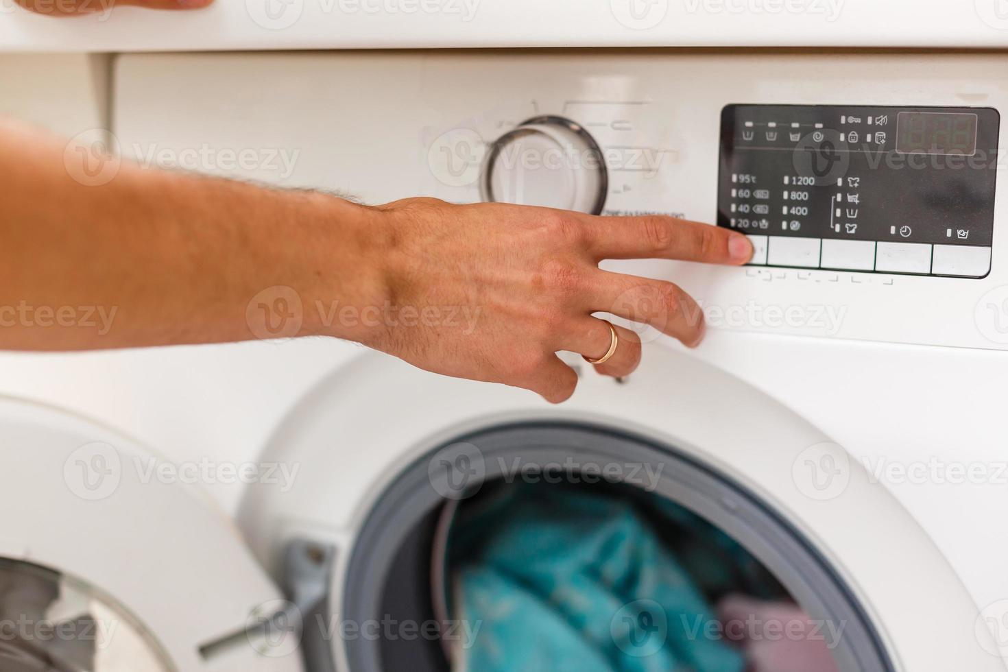 Man loading cloths to washing machine. View from inside the washing machine. photo