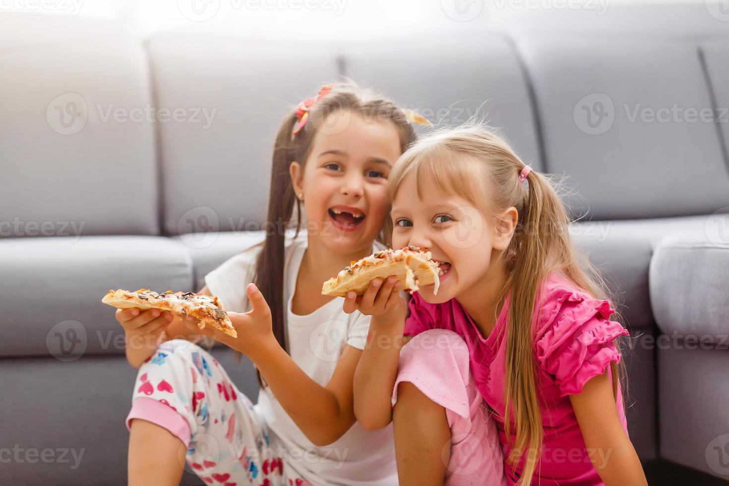 Portrait of cute little girl sitting and eating pizza photo