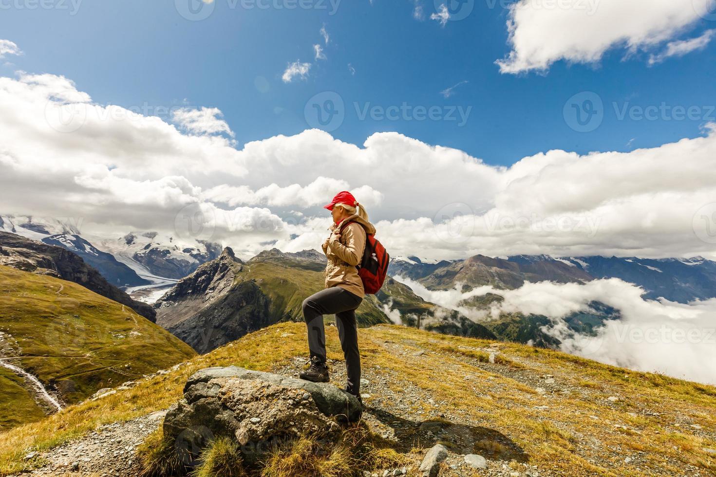 Rear view of a woman with backpack looking at the view Female hiker relaxing on mountain top. photo