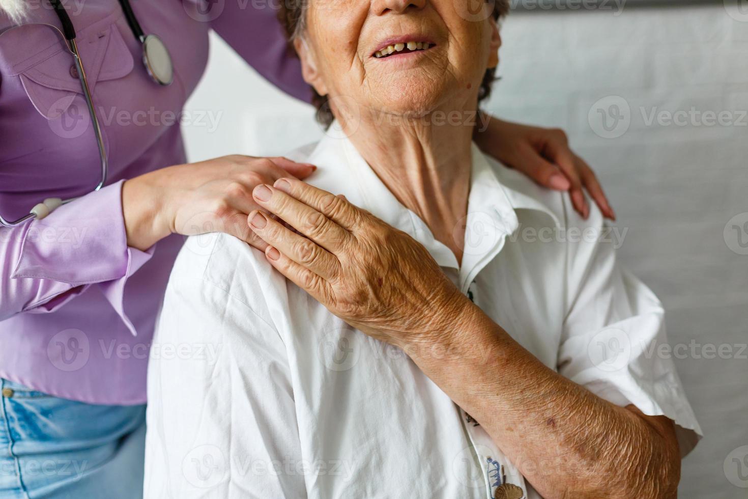 La mano de la niña toca y sostiene las manos arrugadas de una anciana. foto