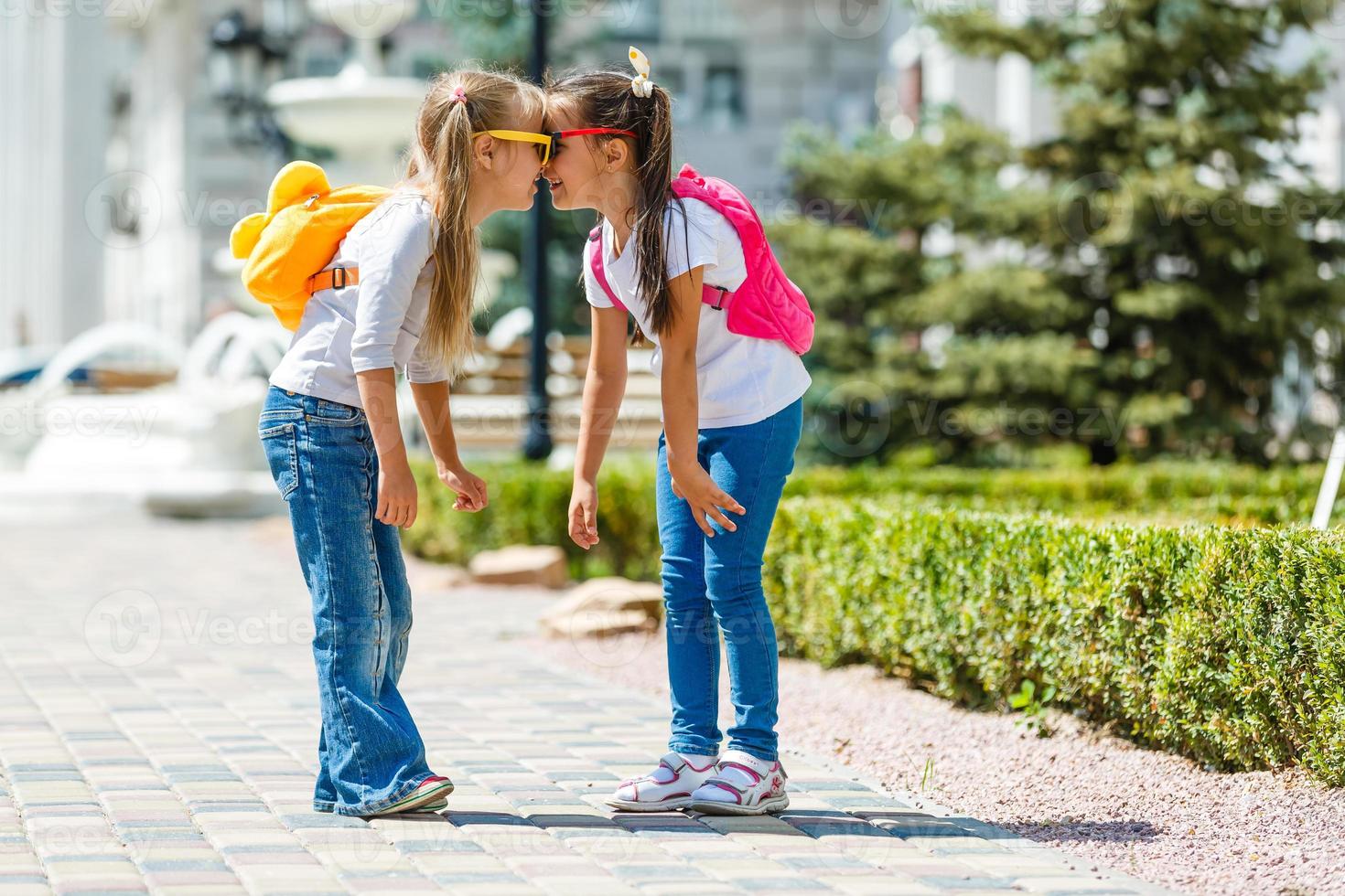 dos escolares con mochila fuera de la escuela primaria. colegiala, estudiante de primaria yendo de la escuela, graduación, vacaciones de verano. foto