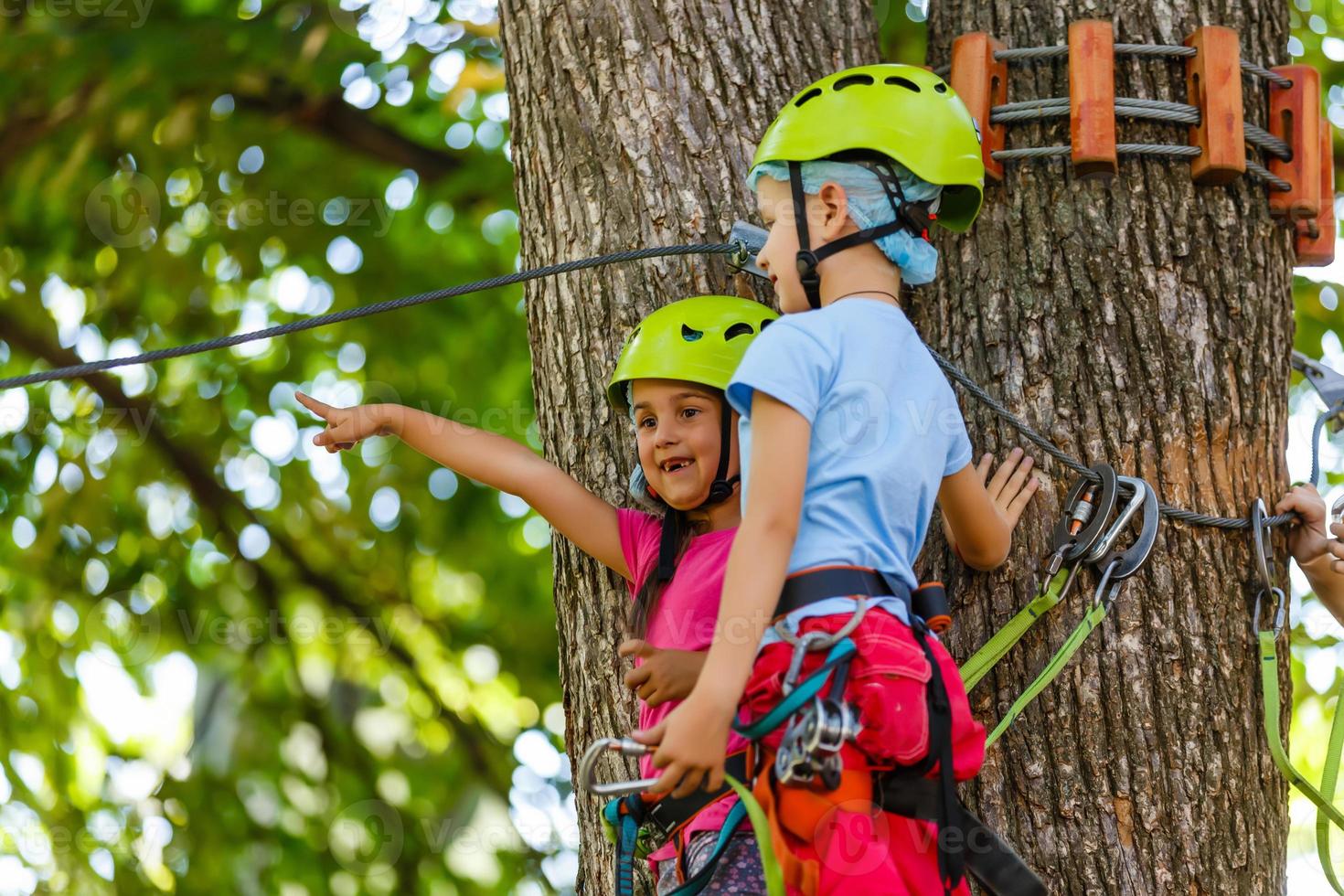 adventure climbing high wire park - children on course rope park in mountain helmet and safety equipment photo