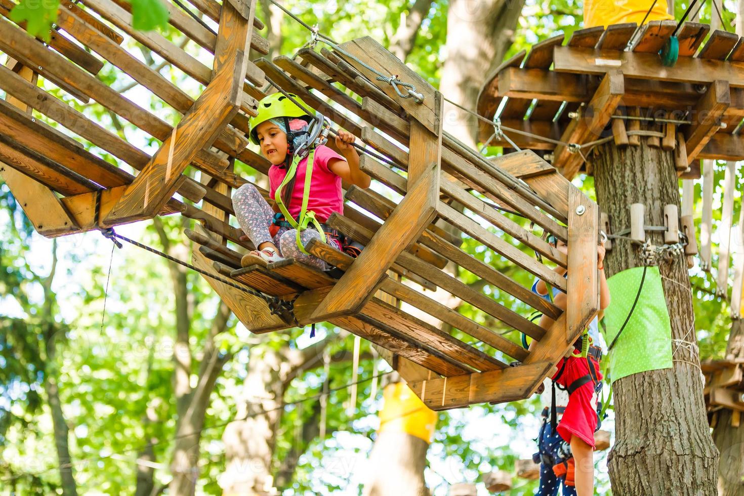 parque de cuerdas de escalada de aventura - niños en el parque de cuerdas del curso en casco de montaña y equipo de seguridad foto