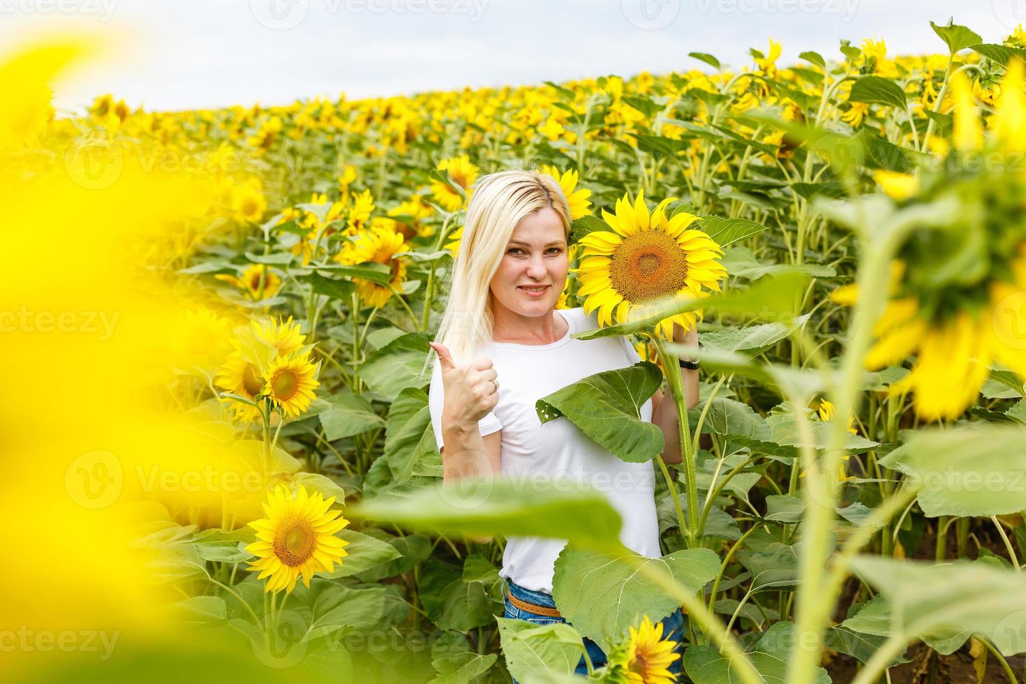woman with sunflowers enjoying nature and laughing on summer sunflower field. photo