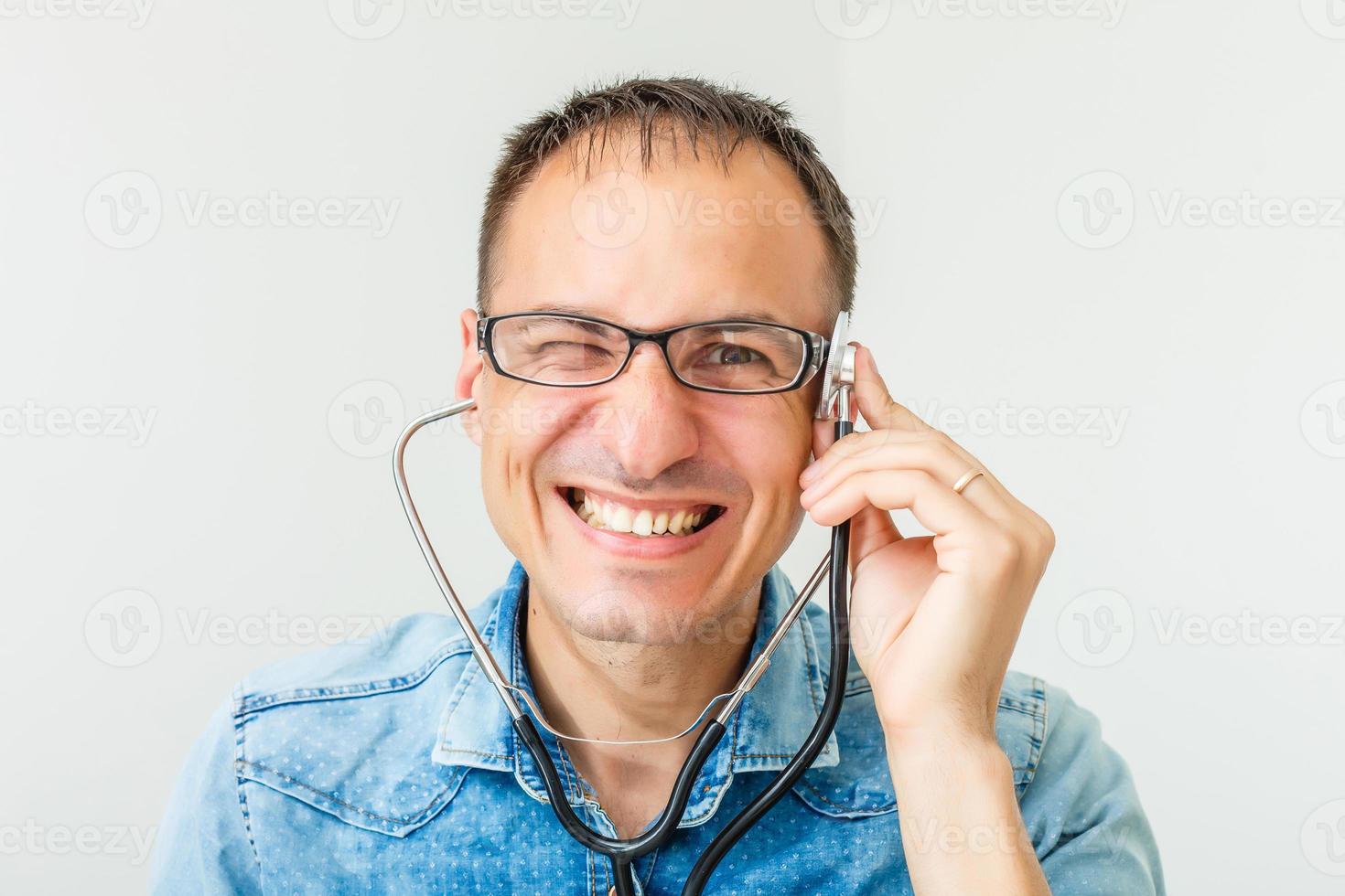 retrato de un joven y alegre doctor de uniforme con fonendoscopio sobre fondo blanco foto