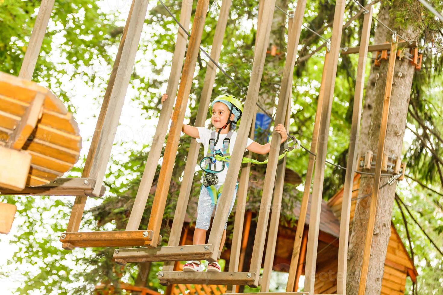 niña feliz en un parque de cuerdas en el fondo de madera foto