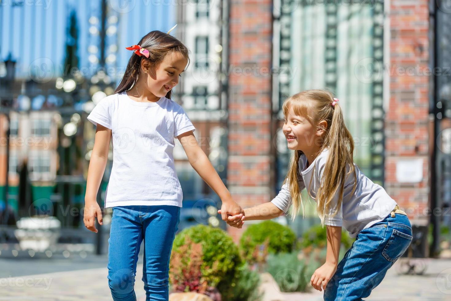 Two beautiful little girls outdoor in the playground at summer time photo