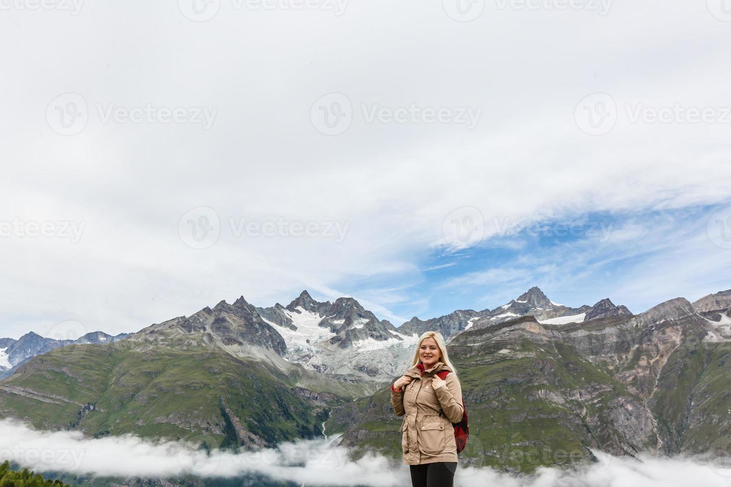 Woman on mountain top of mountain landscape around lake and blue sky. photo