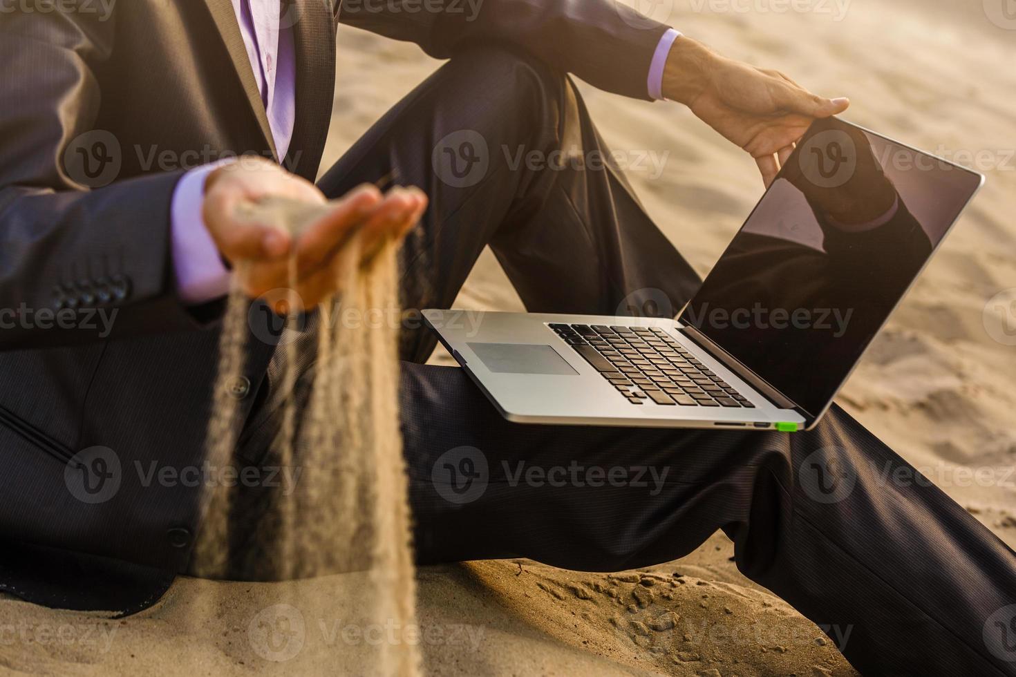 Time is running like the sand through your fingers - time running concept, businessman in suit in the desert photo