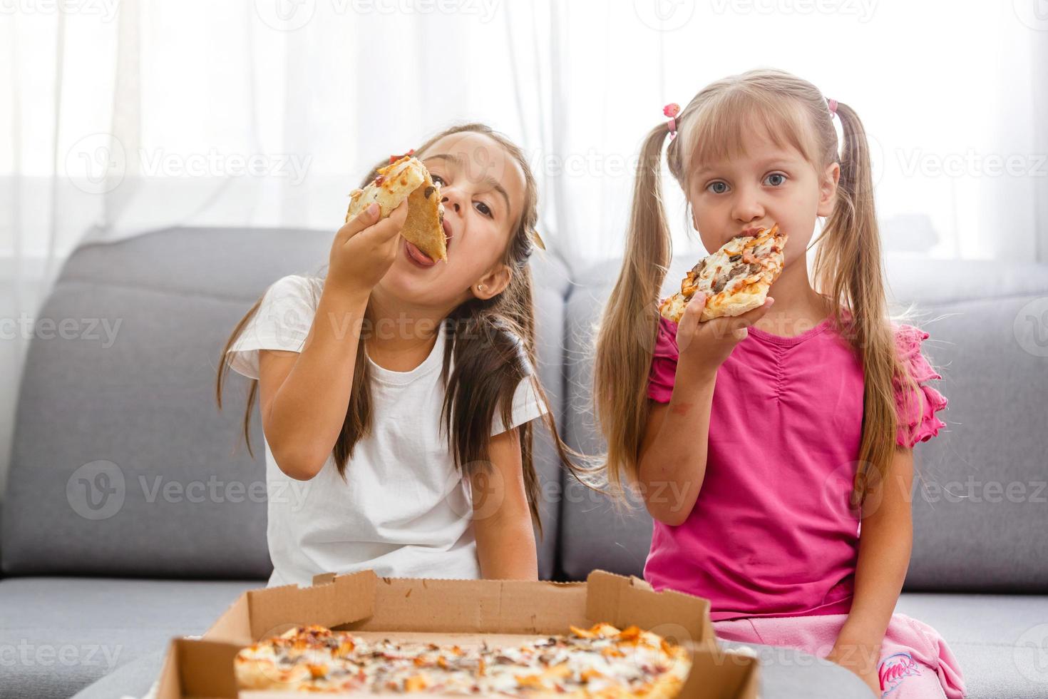 Portrait of cute little girl sitting and eating pizza photo