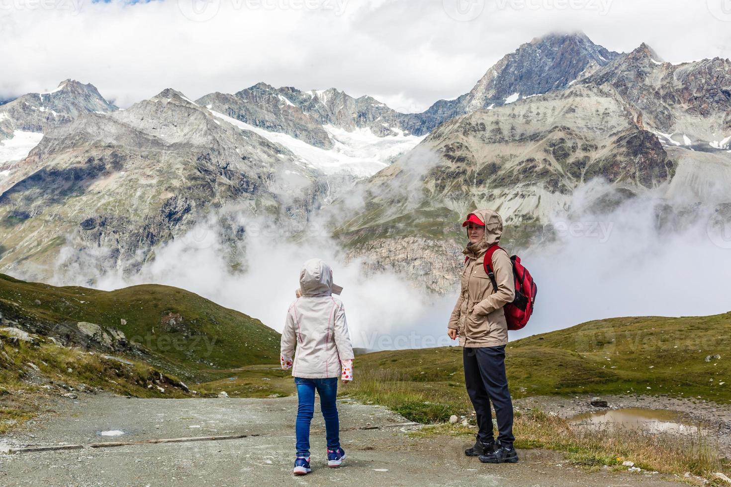 mother and daughter with backpack sitting on the footpath in the mountains at the day time. photo
