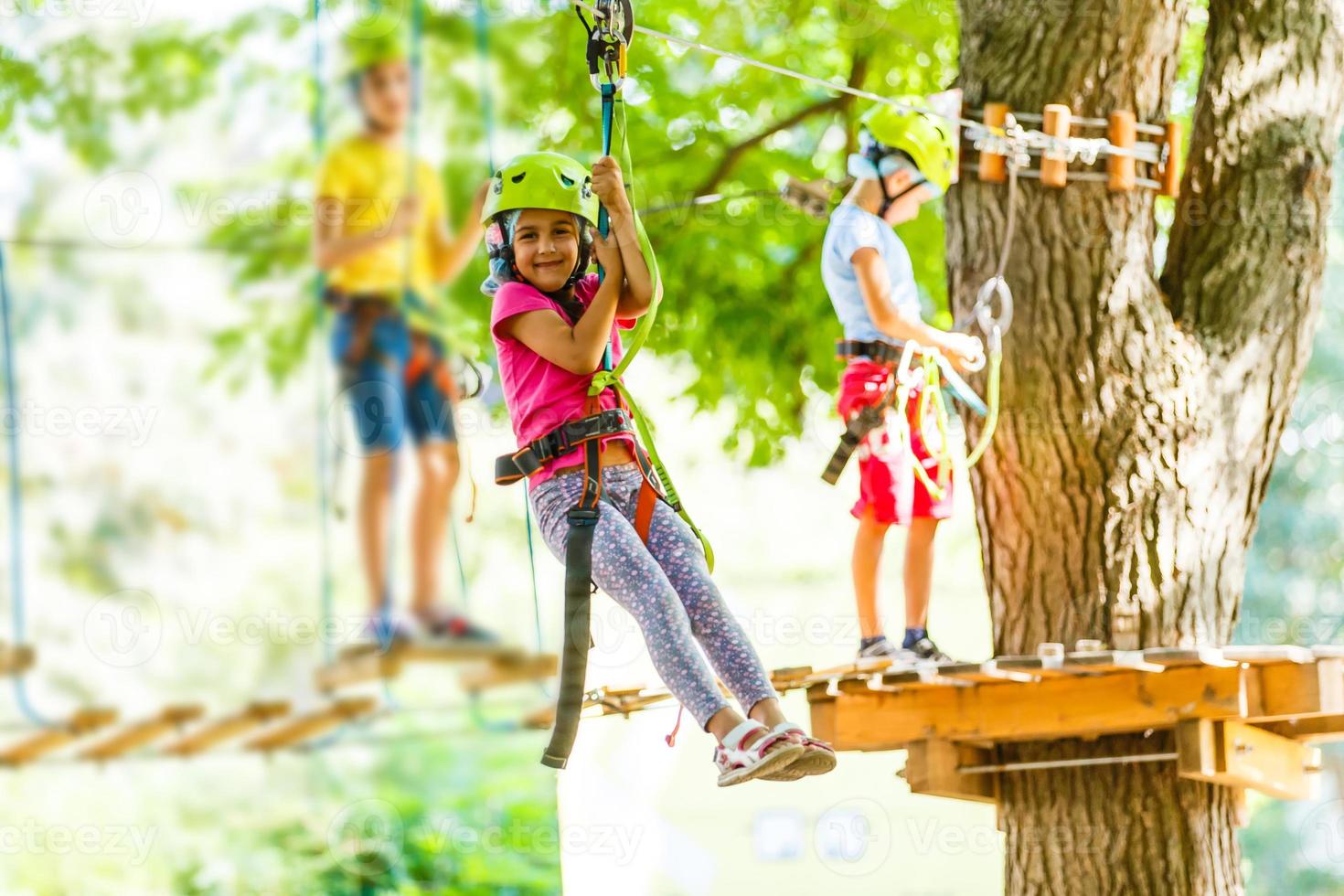 parque de cuerdas de escalada de aventura - niños en el parque de cuerdas del curso en casco de montaña y equipo de seguridad foto