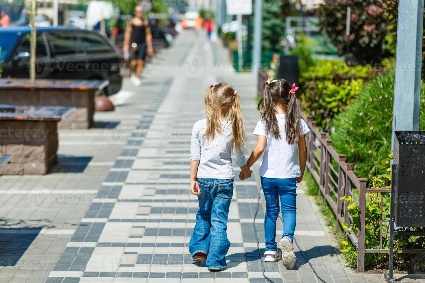 two school girls wearing backpack outside the primary school. schoolgirl, elementary school student going from school, graduation, summer holidays. photo