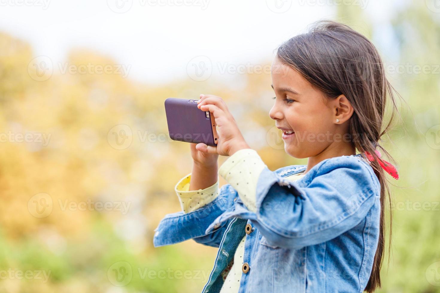 education, school, technology and internet concept - little student girl with smartphone in the park photo