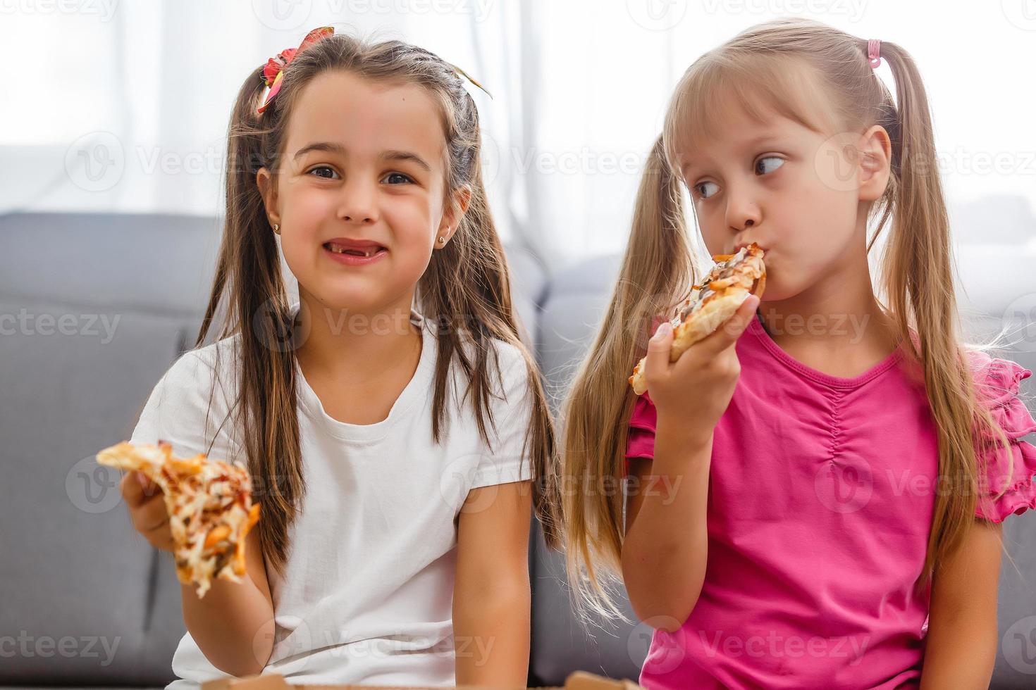 two girls eating pizza home photo