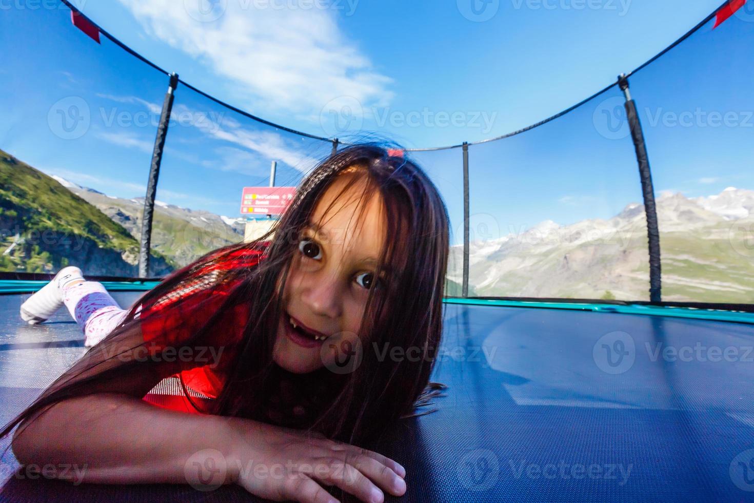 Little girl plays on the playground on the beautiful landscape background in the mountains photo
