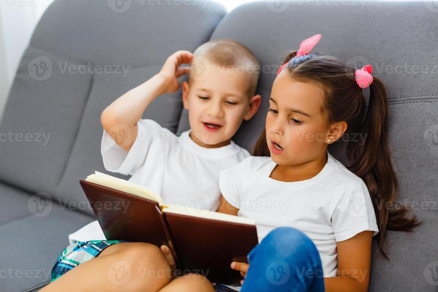 los niños leen un libro en casa foto