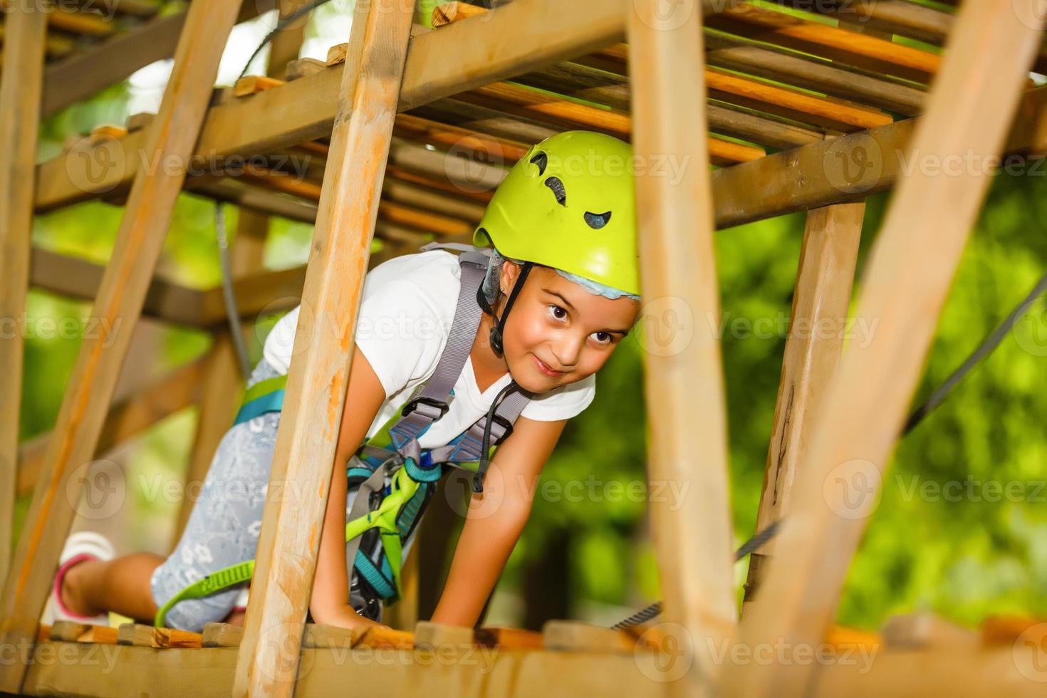 happy little girl in a rope park on the wood background photo