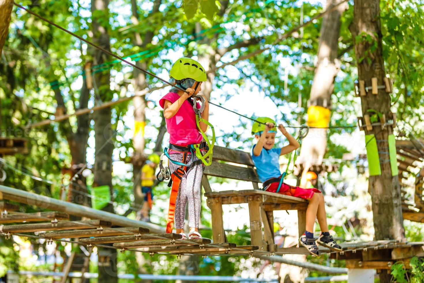 happy little children in a rope park on the wood background photo