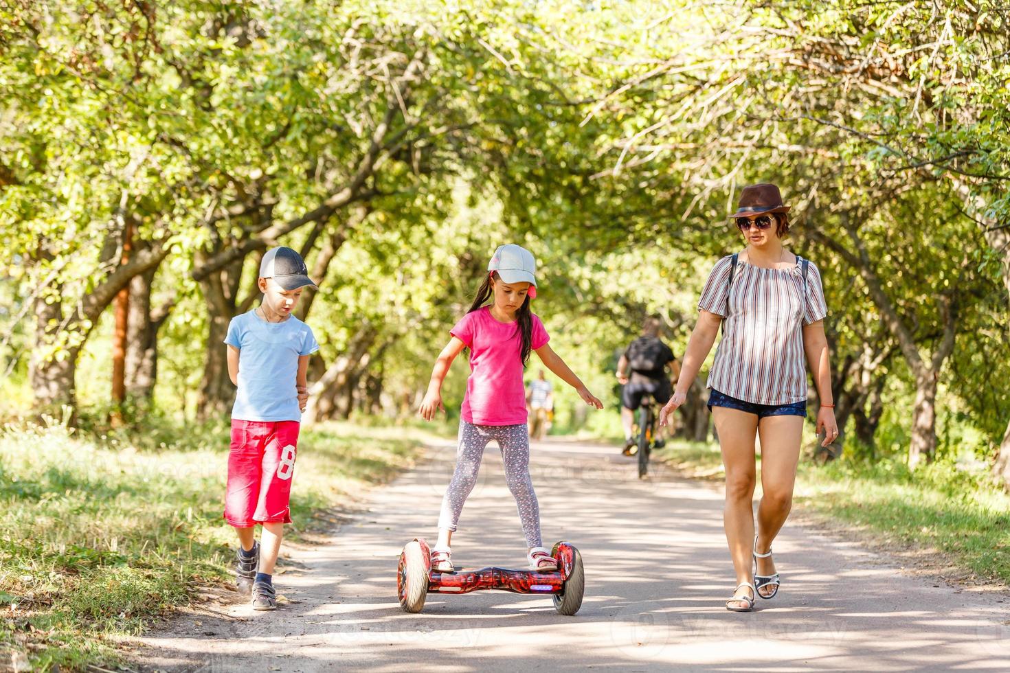 Small girl learns to ride electric mini hoverboard in the city. photo
