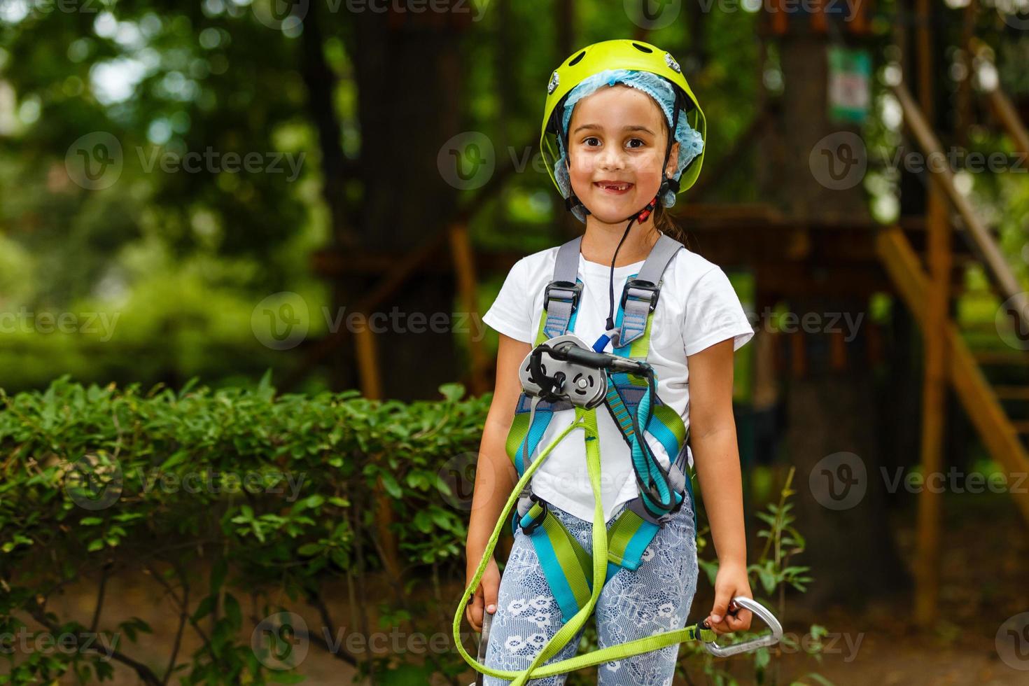 Adorable little girl enjoying her time in climbing adventure park on warm and sunny summer day photo