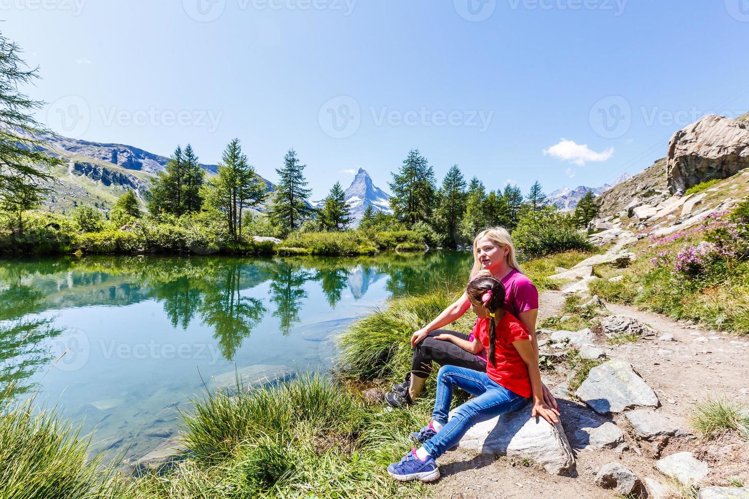 Woman on mountain top of mountain landscape around lake and blue sky. photo