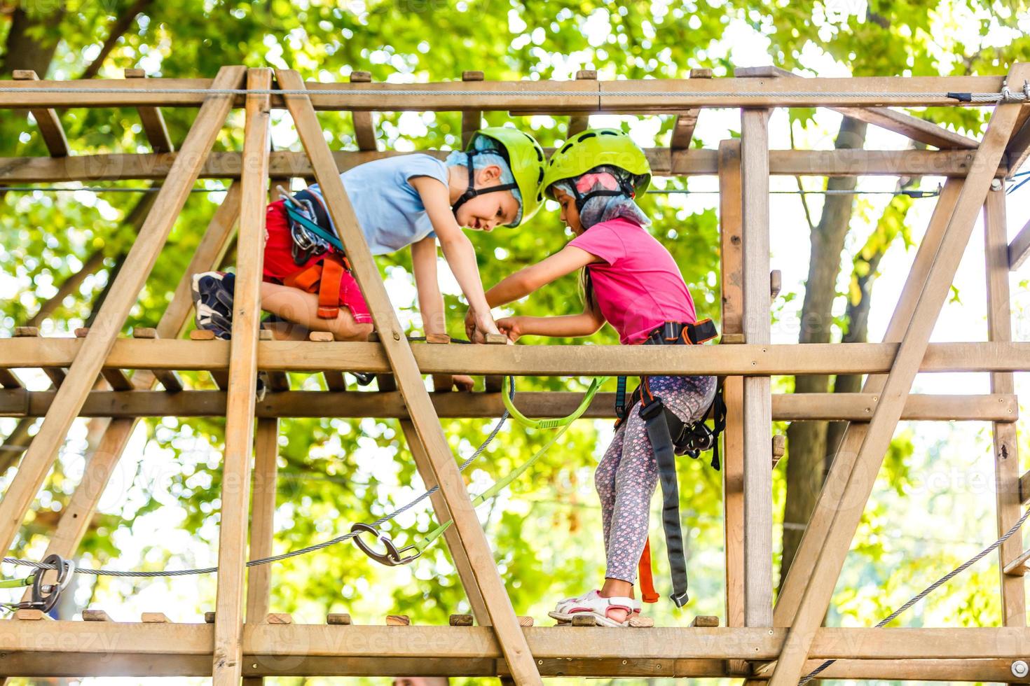 adventure climbing high wire park - children on course rope park in mountain helmet and safety equipment photo