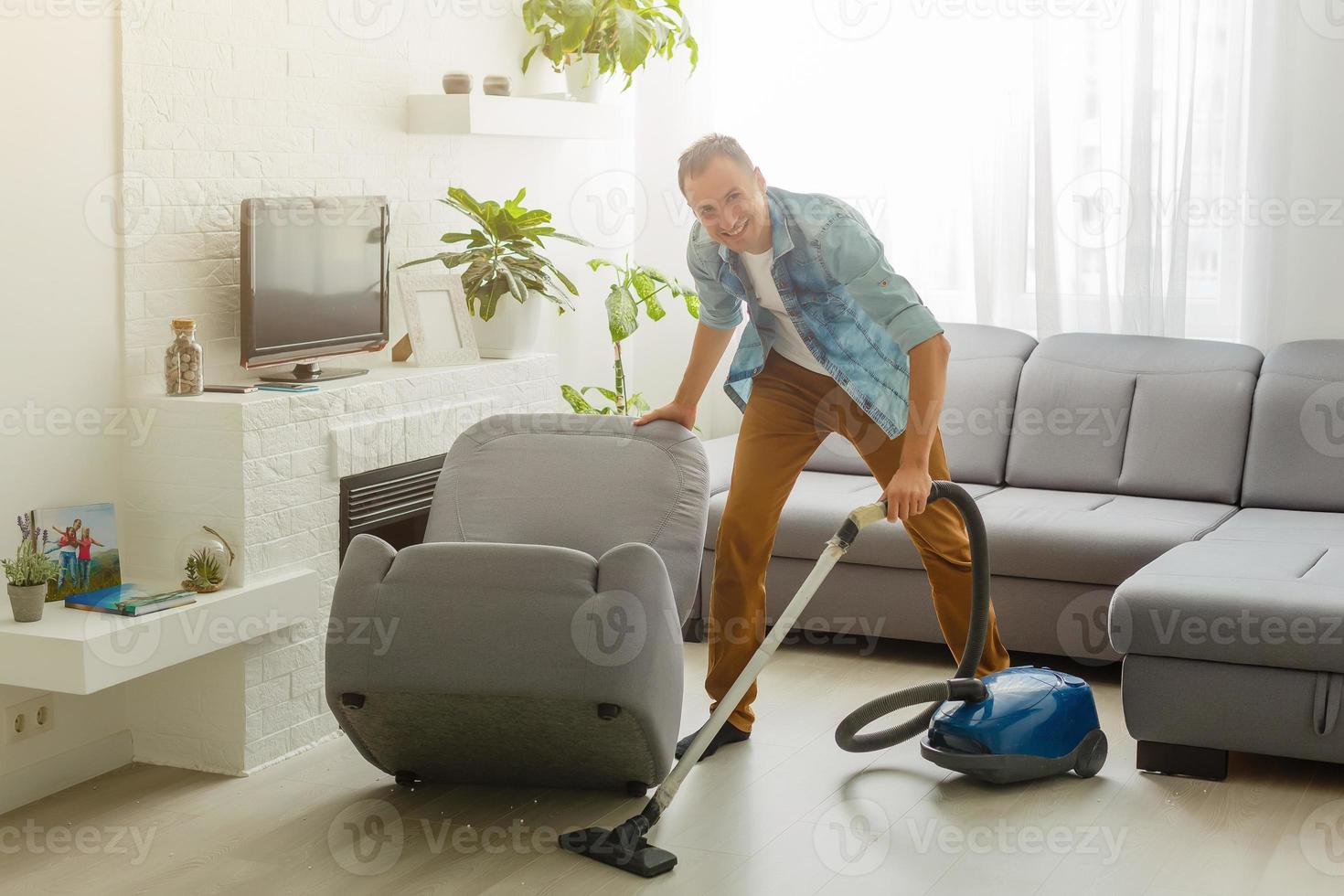 Coronavirus pandemic. A man with a vacuum cleaner in his apartment. Home Office. Quarantine. Remote work. A man in a business shirt and underpants holds. photo