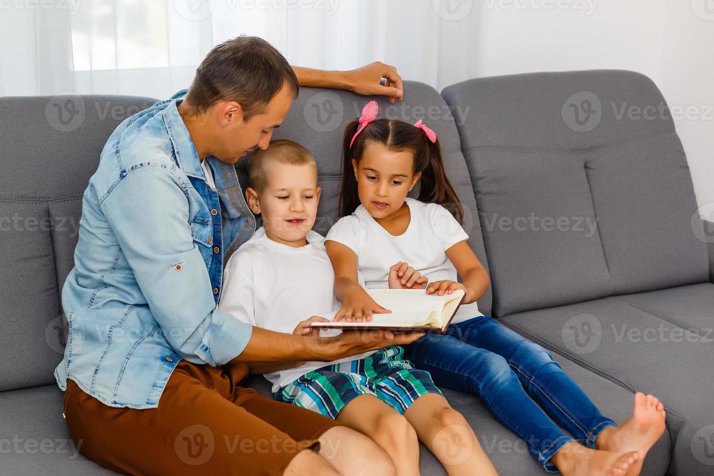 Young father reading book to little children photo