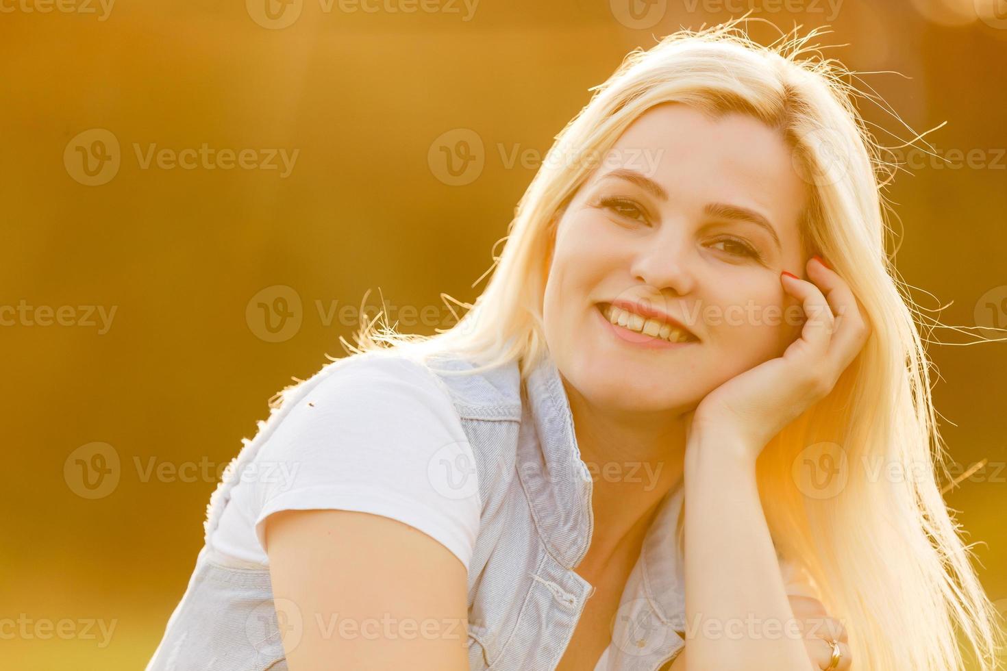 mujer feliz relajándose en el césped. cerrar la cara de una mujer rubia sonriendo y mirando a la cámara. mujer i en un día de verano. foto