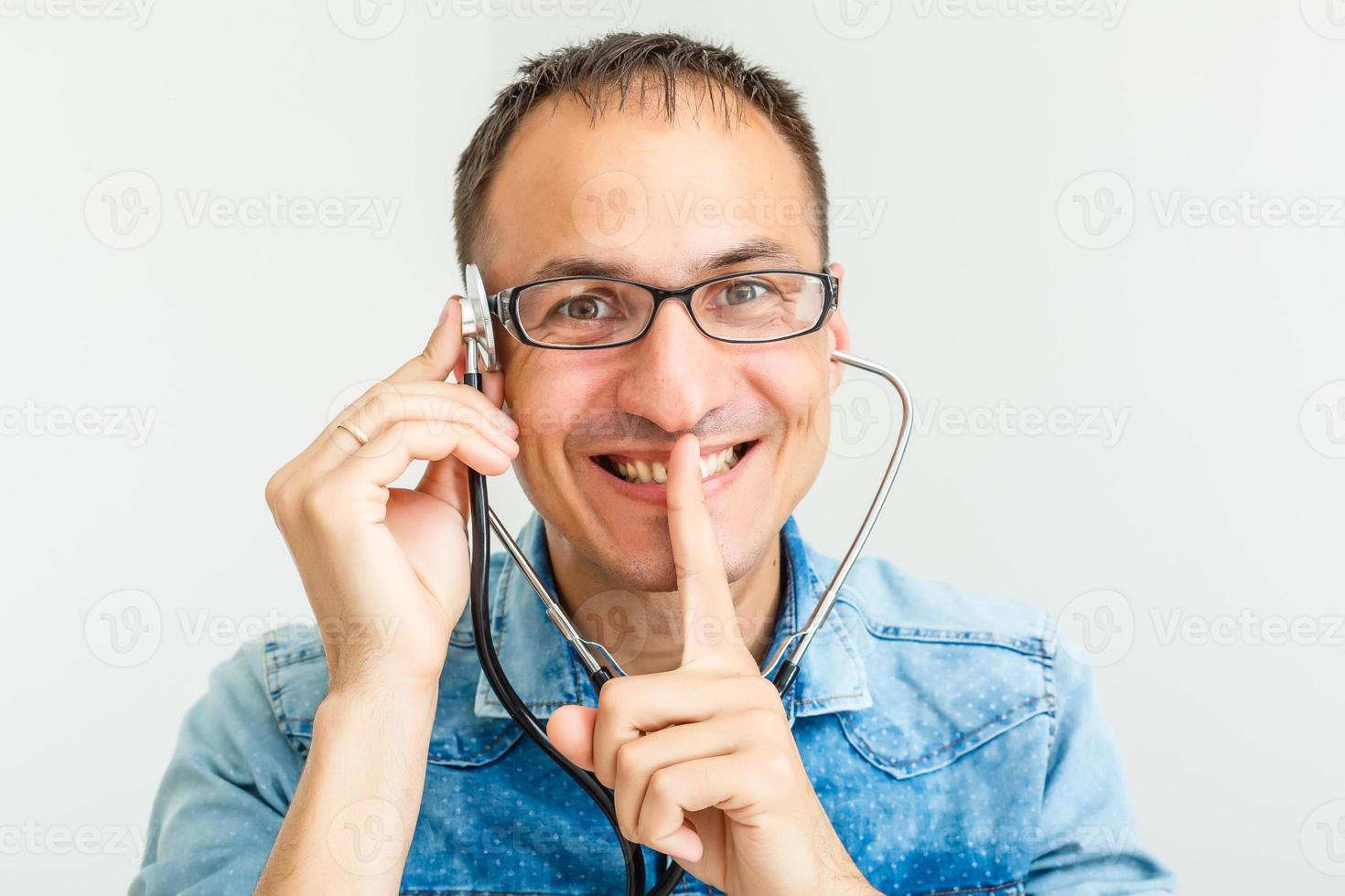 retrato de un joven y alegre doctor de uniforme con fonendoscopio sobre fondo blanco foto