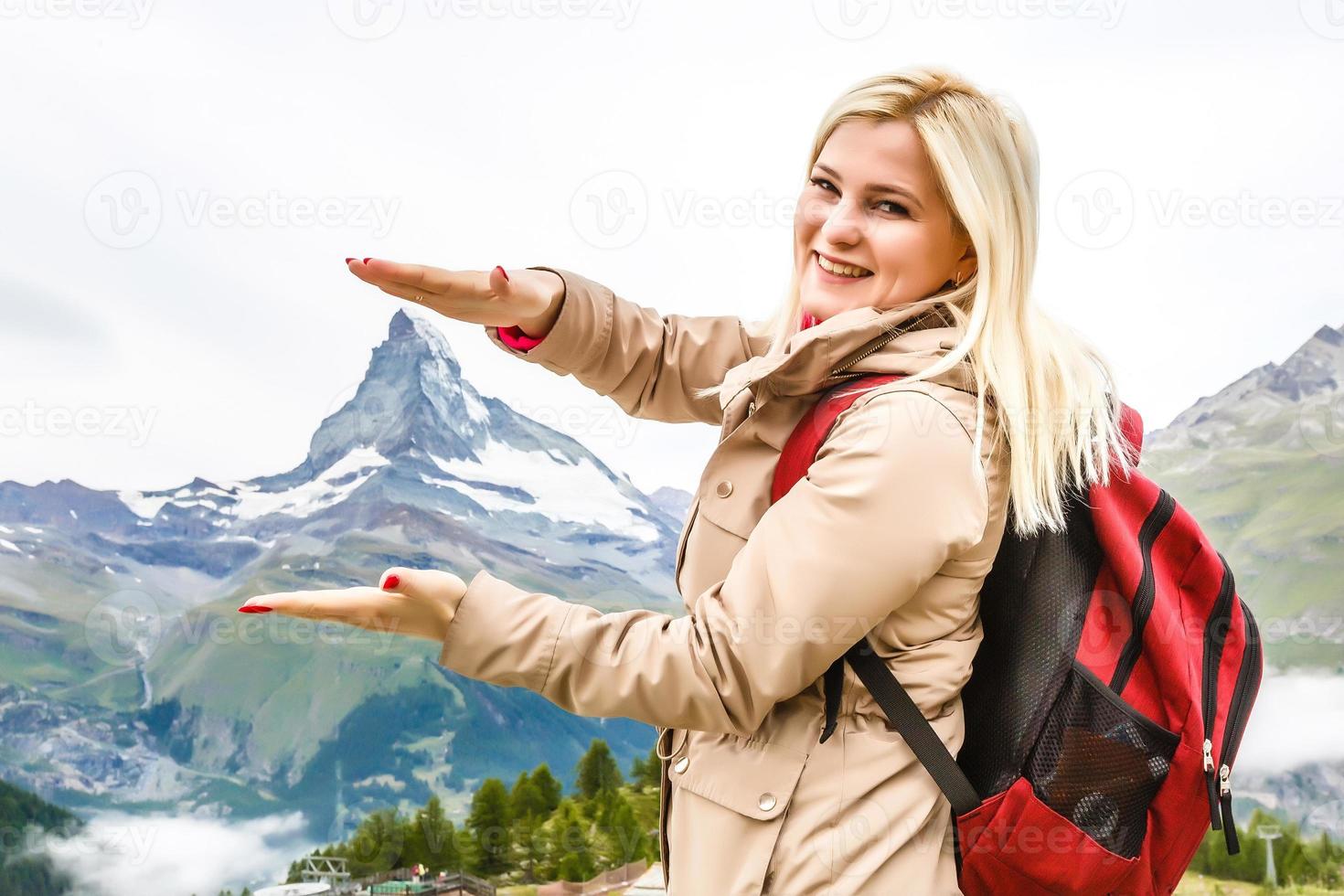 Beautiful young woman hiking in Swiss Alps with famous mount Matterhorn on background. photo