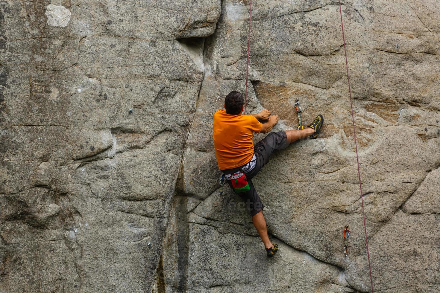 A young woman with a rope engaged in the sports of rock climbing on the rock. photo