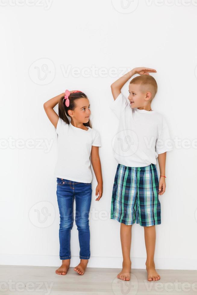 Little boy and girl measuring their height isolated on white background photo