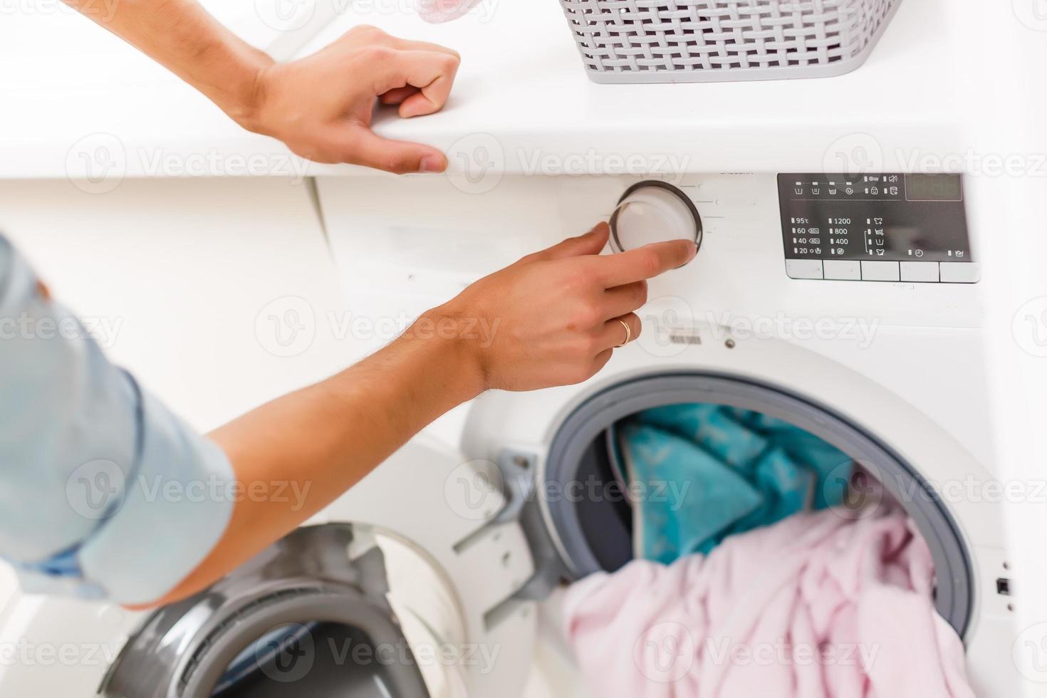 A detail of a male putting in a load of laundry photo