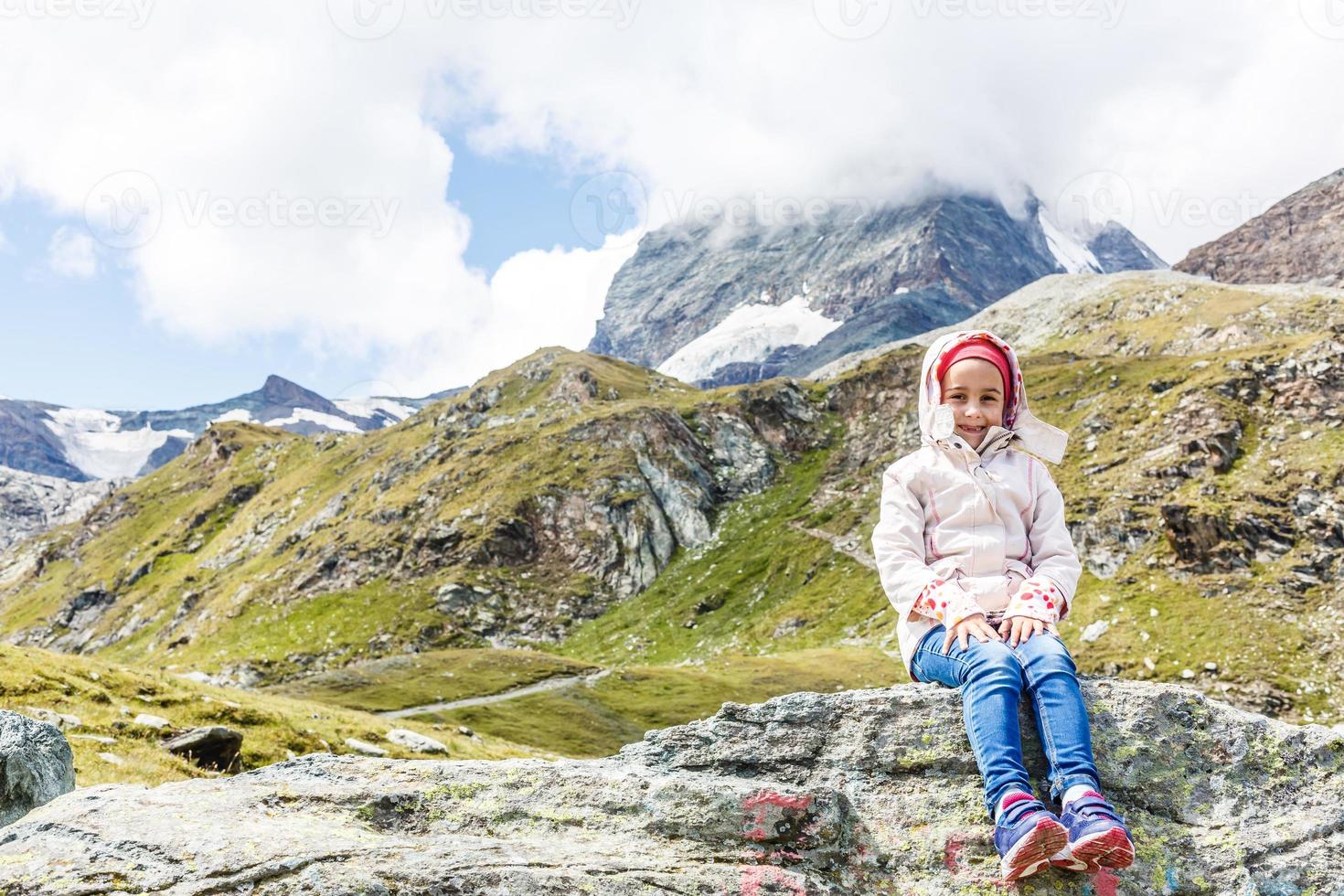 Children hiking in Alps mountains. Kids look at mountain in Austria. Spring family vacation. Outdoor fun and healthy activity. photo