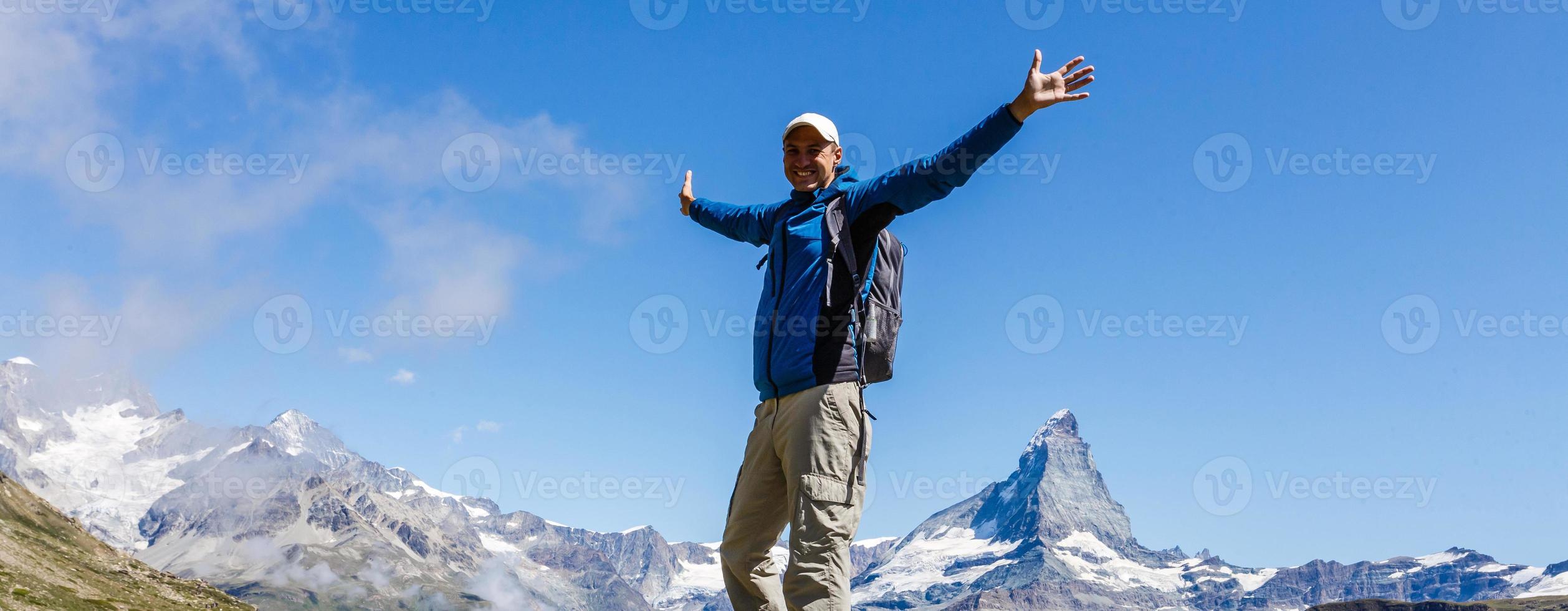 elderly man with a backpack goes on the road to the mountains photo