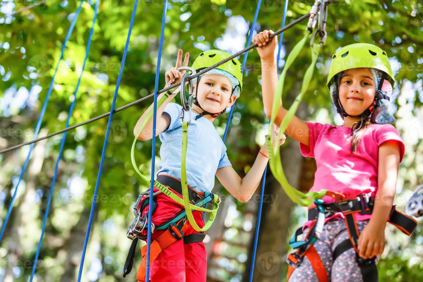 parque de cuerdas de escalada de aventura - niños en el parque de cuerdas del curso en casco de montaña y equipo de seguridad foto