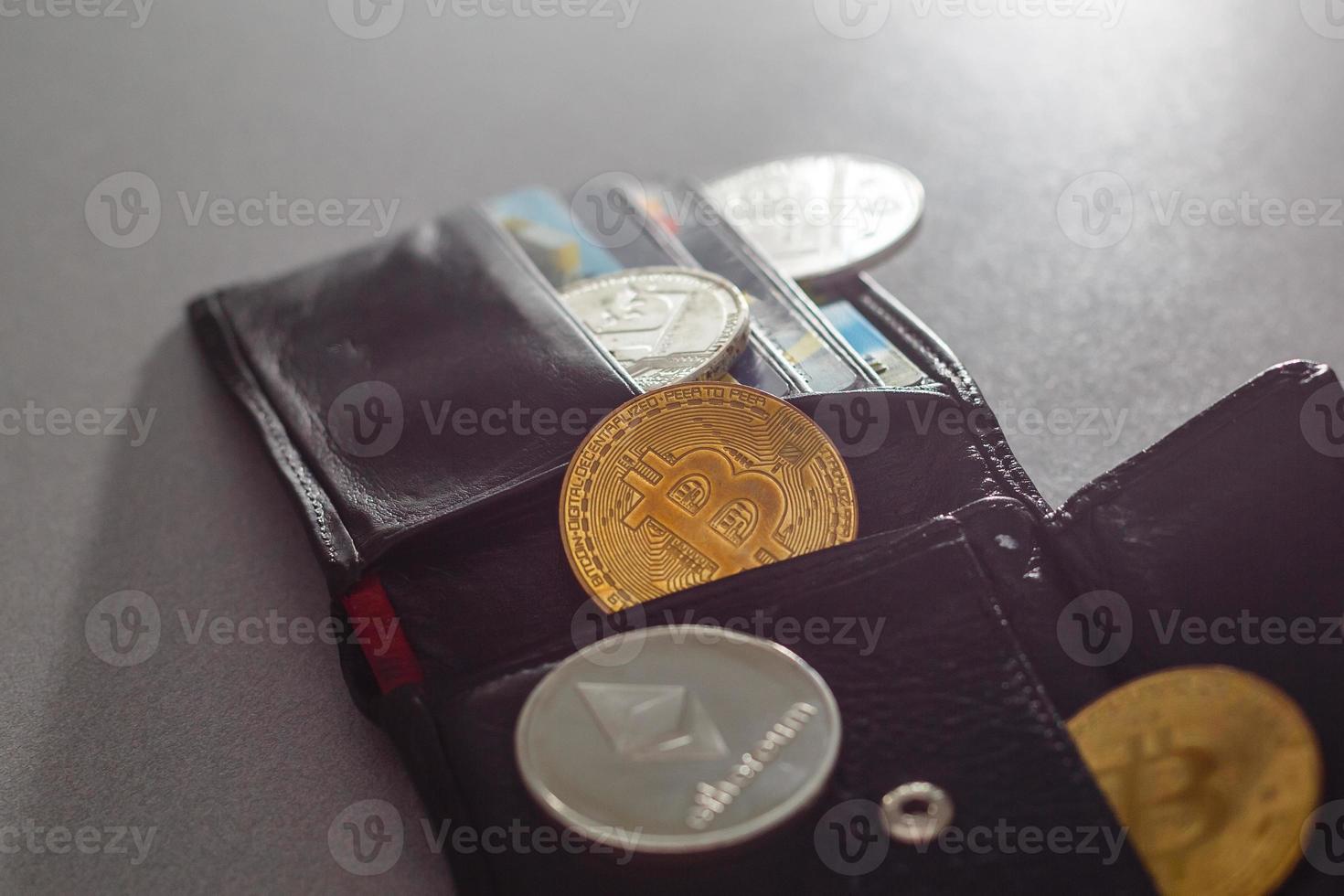 Closed wallet with dollar bills and bitcoins on the wooden table. Business concept. photo