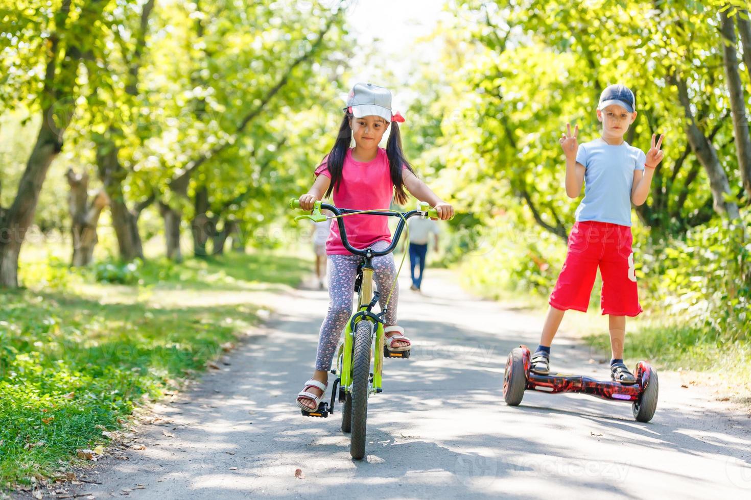 Girl on a bicycle and a boy on a gyroscope are riding together photo