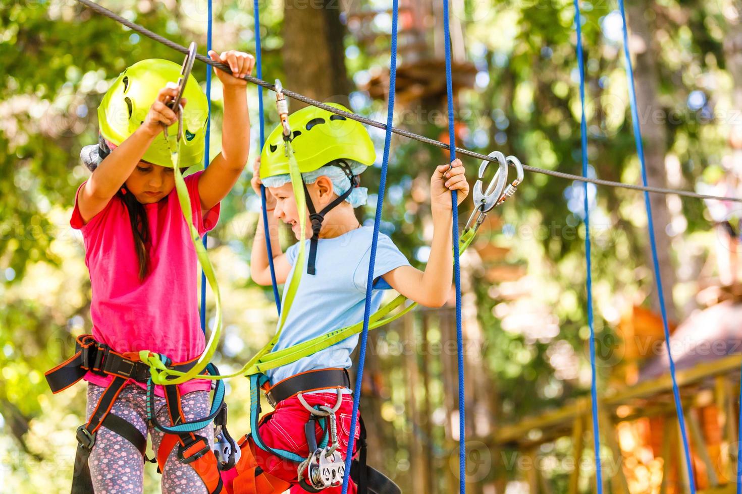 adventure climbing high wire park - children on course rope park in mountain helmet and safety equipment photo