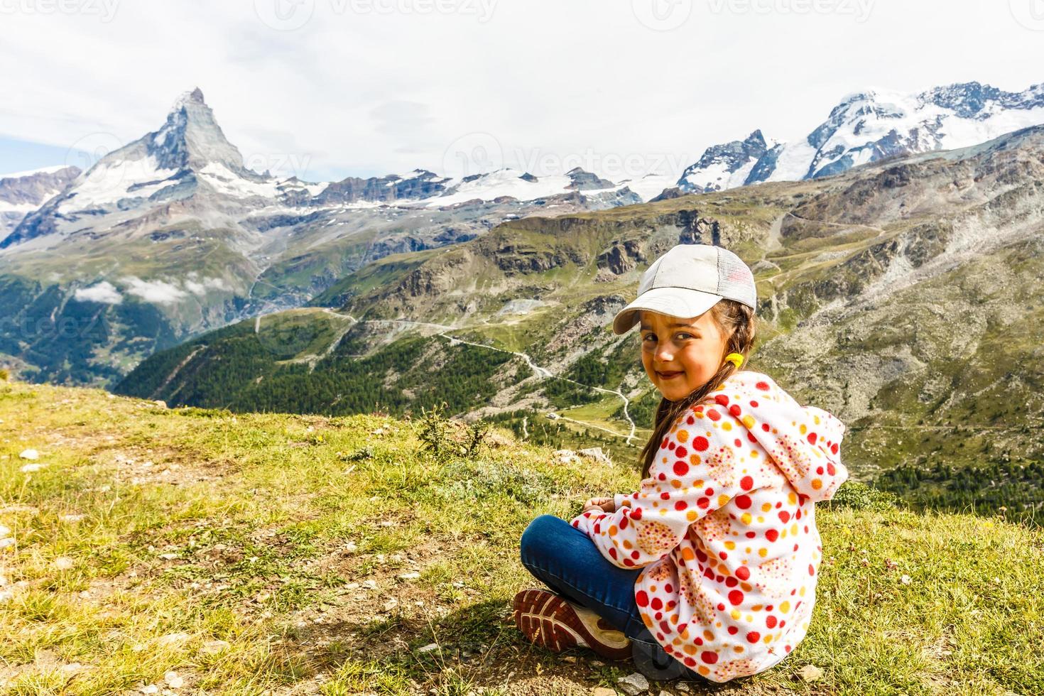 girl with a backpack in Swiss Alps with famous mount Matterhorn on background. photo