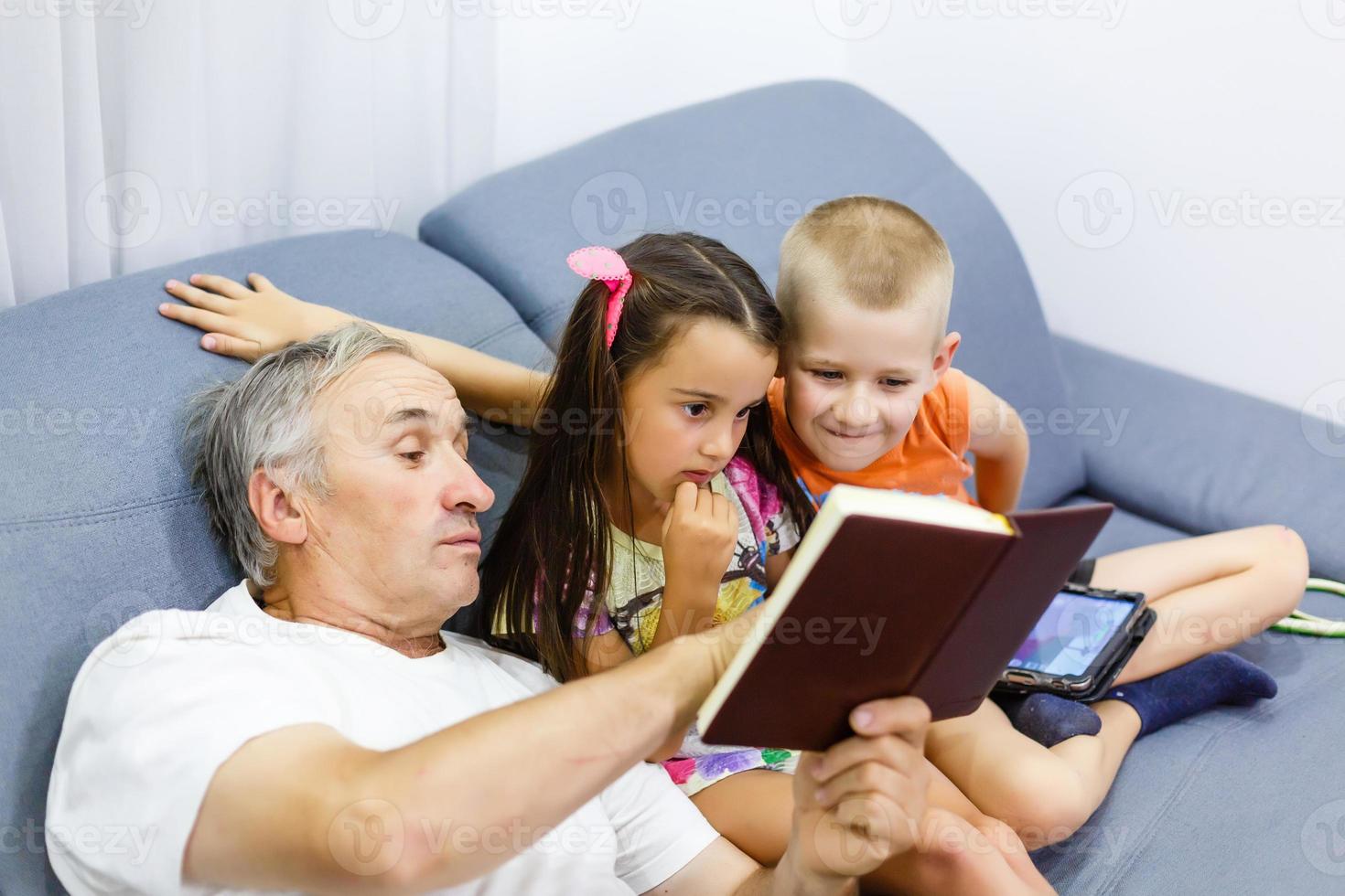 grandfather and grandchildren reading a book photo