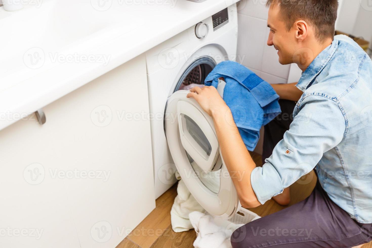 Man loading cloths to washing machine. View from inside the washing machine. photo