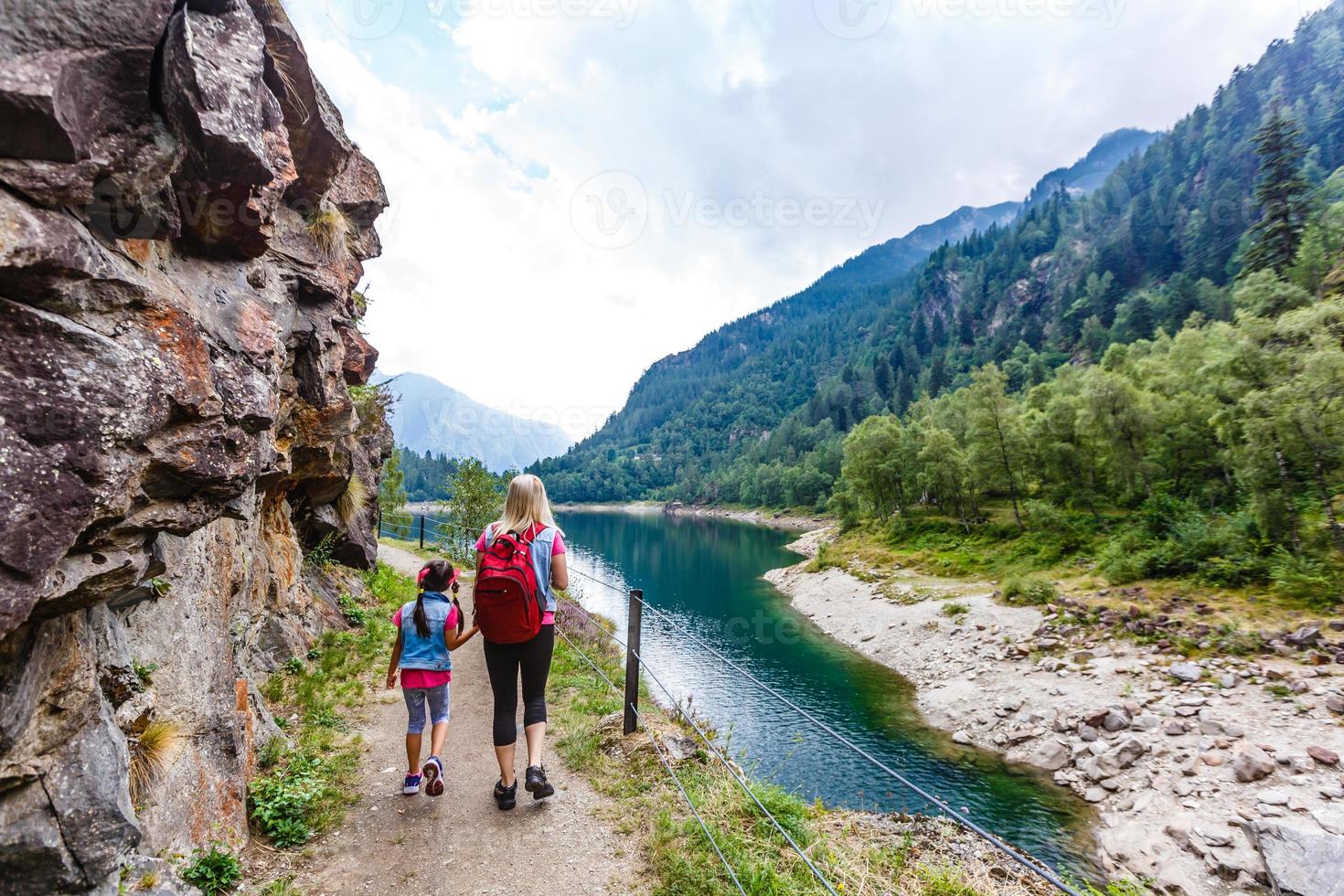 Hikers with backpack looking at mountains, alpine view, mother with child photo