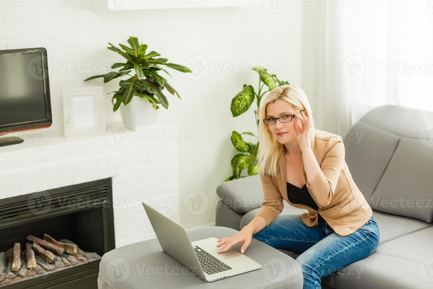 Beautiful young blonde female using portable laptop computer while sitting in a vintage coffee shop.Young beautiful girl using a personal laptop computer to look up information on the internet photo