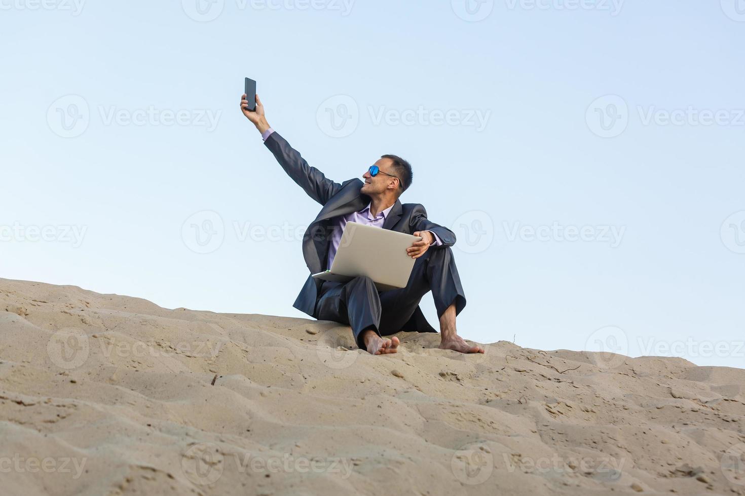Businessman sitting alone in the empty desert photo
